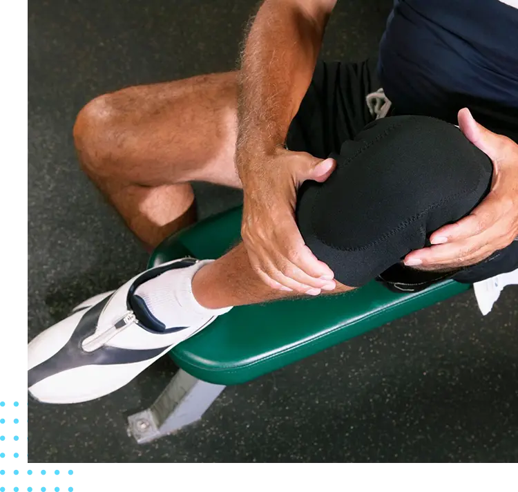 A man sitting on top of a bench holding his knee.